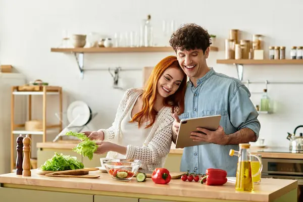 Una joven pareja disfruta cocinando juntos en una acogedora cocina, uniéndose a ingredientes frescos. - foto de stock
