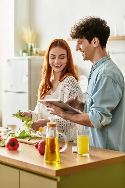 Couple enjoys quality time in the kitchen, laughing and preparing fresh ingredients for dinner. — Stock Photo