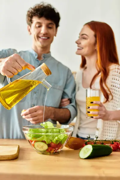 A couple shares fun at home, laughing while cooking a fresh, vibrant salad together. — Stock Photo