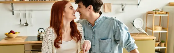 Joyful young couple enjoys each others company while preparing a meal in their cozy kitchen. — Stock Photo