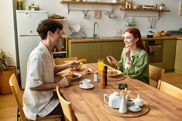 A young couple enjoys quality time together at home, sharing smiles and a delightful meal. — Stock Photo