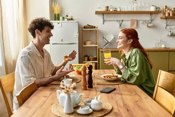 Young couple enjoys a delightful meal at home, sharing laughter and quality moments over food. — Stock Photo