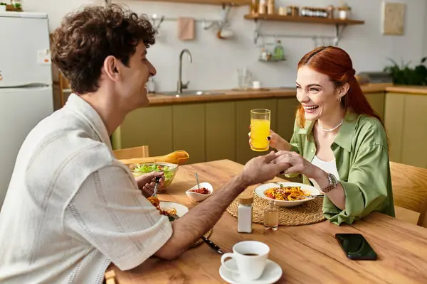 Una encantadora pareja comparte risas y platos mientras disfruta de una comida en su acogedora cocina casera. - foto de stock
