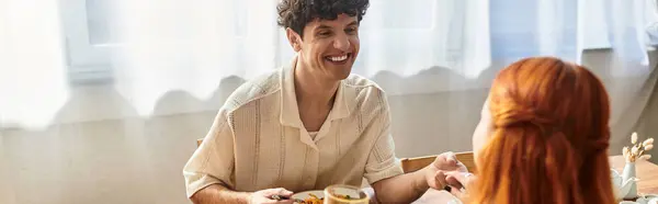 A young couple shares laughter and joy while enjoying a meal in their cozy home. — Stock Photo