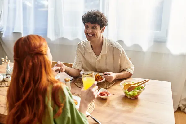 Joyful couple shares laughter and a delicious meal together at home. — Stock Photo