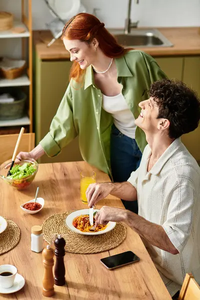 A loving couple laughs together at home while sharing a delicious meal, creating joyful memories. — Stock Photo