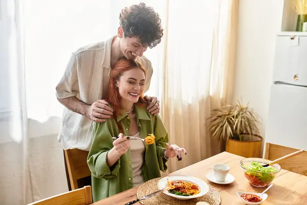 Una giovane coppia condivide un pasto caldo, godendo di gioia e connessione nella loro casa accogliente. — Foto stock