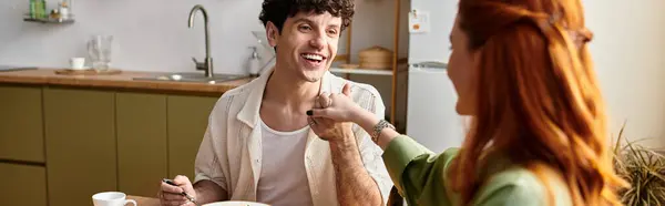 A young couple enjoys a joyful meal at home, bonding over food and laughter. — Stock Photo