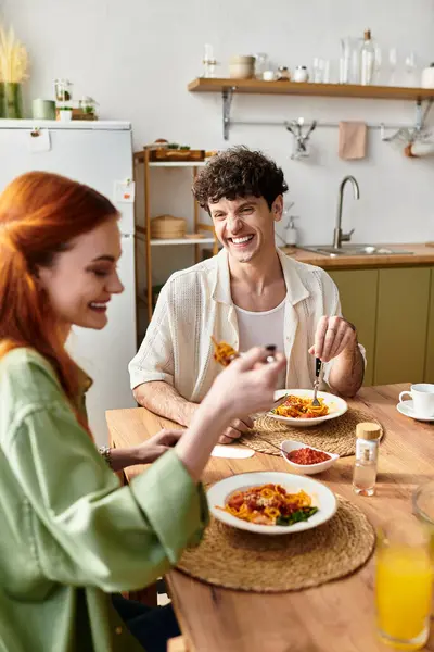Two young lovers share laughter and a delicious homemade meal at home, creating joyful memories. — Stock Photo
