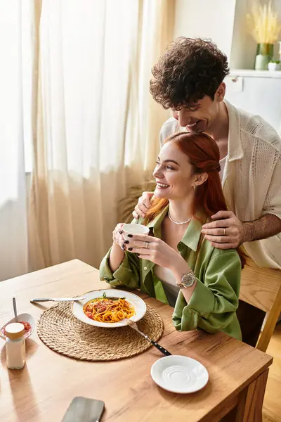 A young couple shares a joyful meal at home, laughing and connecting together. — Stock Photo