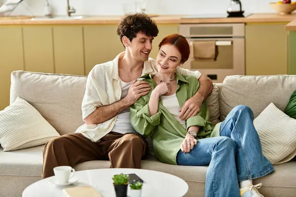 A young couple shares a tender moment on their comfortable couch, embracing each other with joy. — Stock Photo