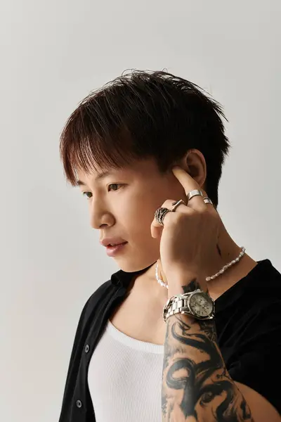 Young handsome Asian man with stylish attire poses thoughtfully against a neutral backdrop. — Stock Photo