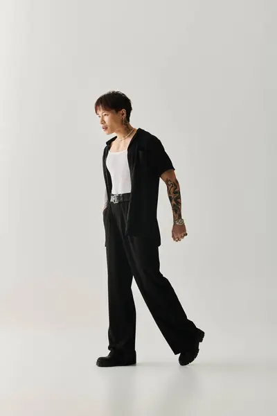 A young, handsome Asian man showcases his stylish outfit against a clean, minimalist backdrop. — Stock Photo