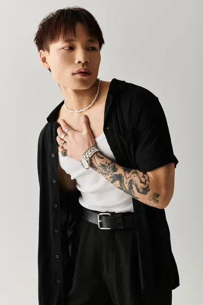 A young Asian man confidently shows off his stylish outfit, blending elegance and edge. — Stock Photo