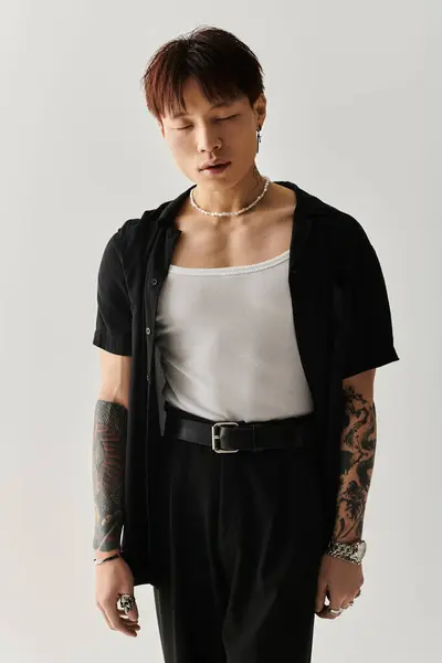 Trendy young man showcases unique style with tattoos and a fashionable outfit in a modern setting. — Stock Photo