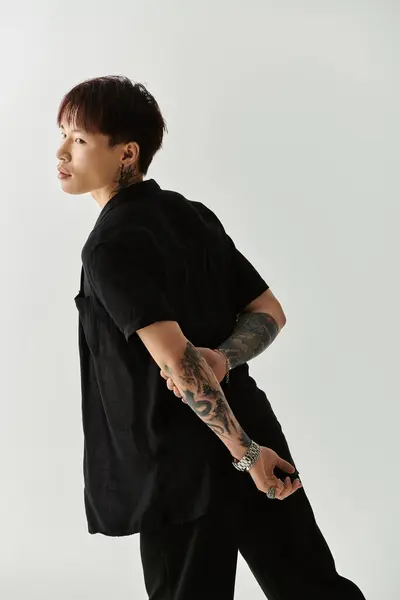 A stylish young man confidently poses in a fashionable outfit against a light background. — Stock Photo