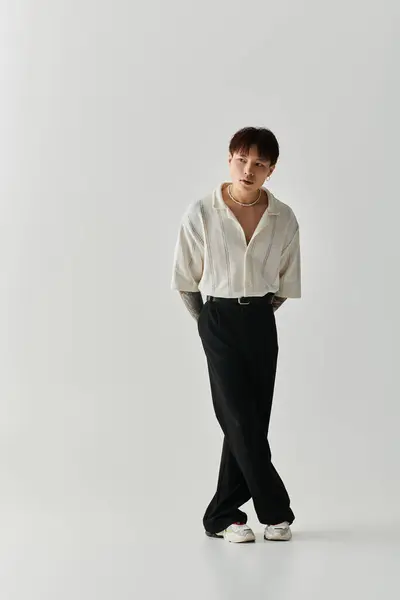 A stylish young Asian man confidently poses in a minimalistic studio, highlighting modern fashion. — Stock Photo