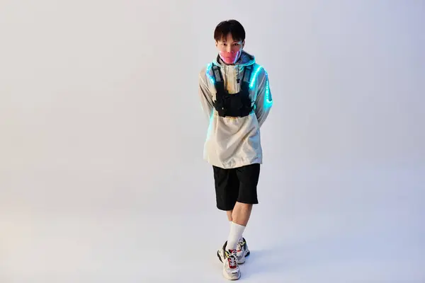 Confident young man in a trendy outfit stands under vibrant lights in a modern space. — Stock Photo