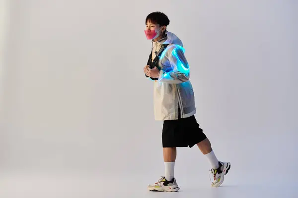 Fashionable Asian man walks confidently, showcasing his trendy attire and illuminated backpack. — Stock Photo