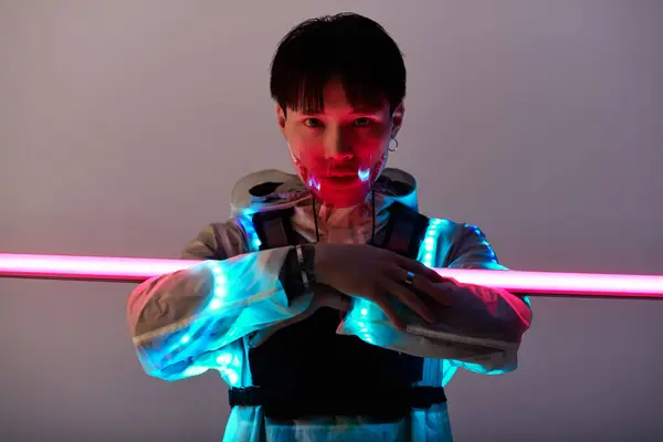 A young, handsome Asian man stands confidently in a striking outfit with glowing lights. — Stock Photo