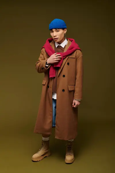 Dressed in a chic brown coat and blue beanie, a young Asian man showcases his fashion sense. — Stock Photo