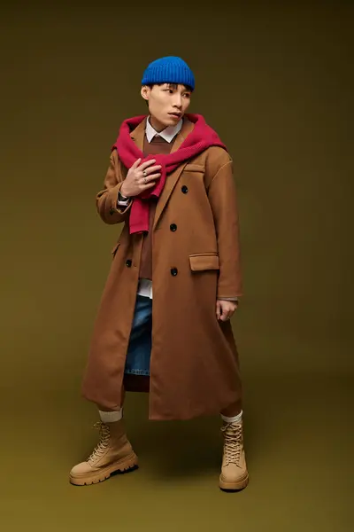 Stylish young Asian man stands confidently, wearing a striking outfit against a warm background. — Stock Photo