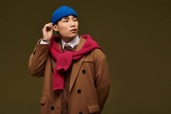 A young handsome man with a blue beanie and stylish outfit showcases a unique urban look. — Stock Photo