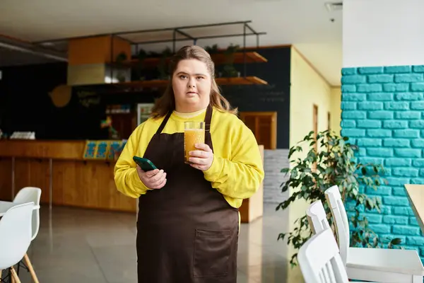 Una joven con síndrome de Down sonríe con confianza en un vibrante café, sosteniendo una bebida. - foto de stock