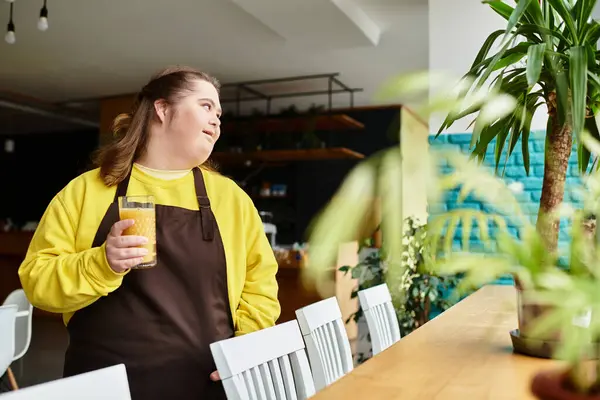 A confident young woman with Down syndrome holds a drink in a cafe, looking around. — Stock Photo