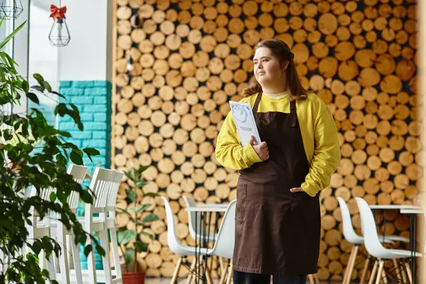 Mujer joven con síndrome de Down se encuentra orgullosamente en un café casual, exudando confianza y fuerza. — Stock Photo