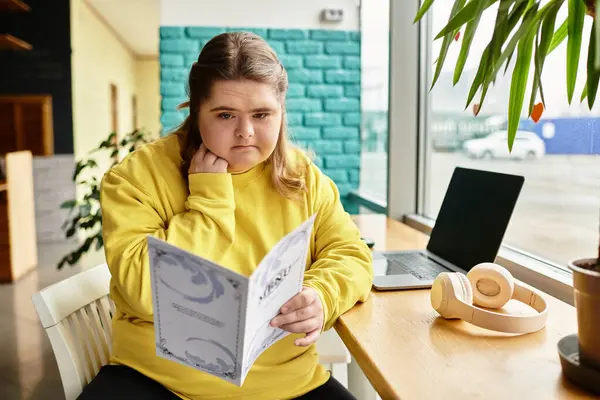 In a cozy cafe, a young woman with Down syndrome sits at a table, thoughtfully browsing the menu. — Stock Photo