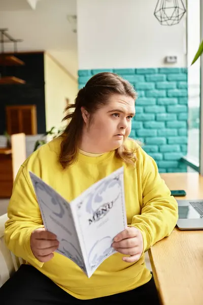 A confident young woman with Down syndrome sits in a cozy cafe, examining the menu. — Stock Photo
