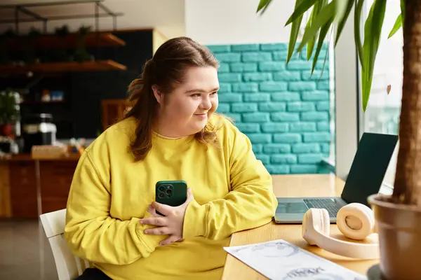 Giovane donna con sindrome di Down si siede a un tavolo da caffè, fidanzato e felice durante l'utilizzo del suo smartphone. — Stock Photo