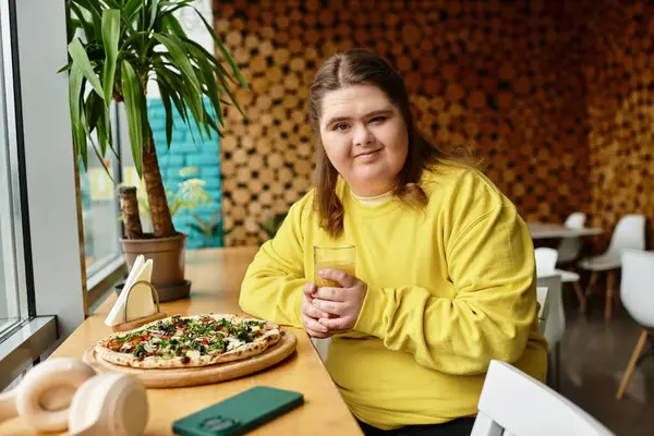 In a bright cafe, a confident young woman with Down syndrome relaxes while savoring pizza. — Stock Photo