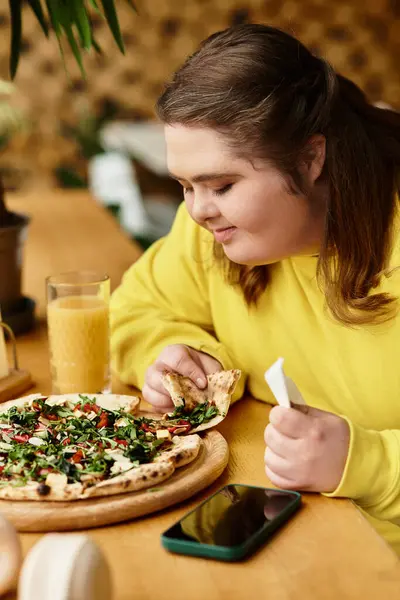 Young woman enjoying a colorful pizza and refreshing drink in a cozy cafe atmosphere — Stock Photo