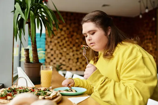 Eine junge Frau mit Down-Syndrom genießt ihr Essen und strahlt im Café Zuversicht aus. — Stockfoto
