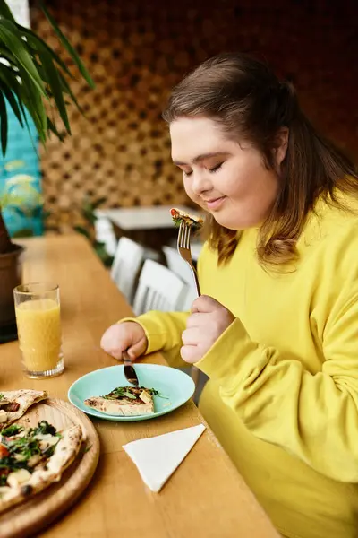 Eine junge Frau mit Down-Syndrom lächelt glücklich, während sie ein leckeres Gericht in einem lebhaften Café genießt. — Stockfoto