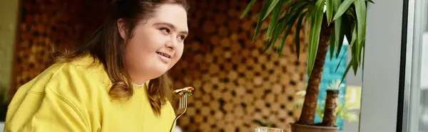 Eine selbstbewusste junge Frau mit Down-Syndrom sitzt in einem Café, genießt ihr Essen und lächelt herzlich. — Stockfoto