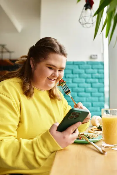 In einem warmen und einladenden Café lächelt eine junge Frau mit Down-Syndrom, während sie ihr Essen genießt. — Stockfoto