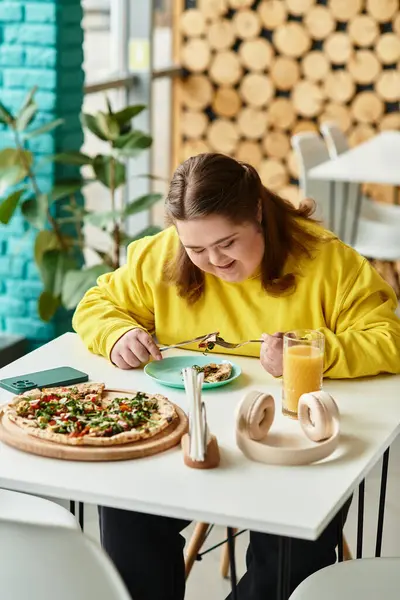 Eine junge Frau mit Down-Syndrom genießt ihre Mahlzeit, während sie an einem hellen Cafétisch sitzt. — Stockfoto