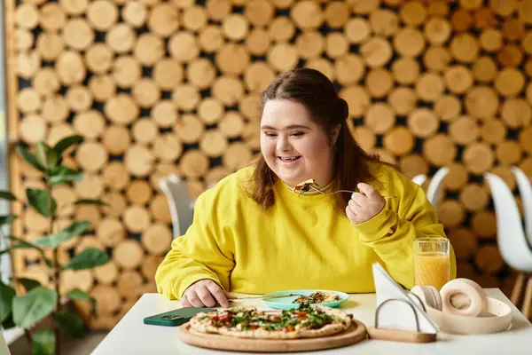 In un accogliente bar, una giovane donna con la sindrome di Down gode felicemente di un pasto gustoso alla sua tavola.. — Foto stock