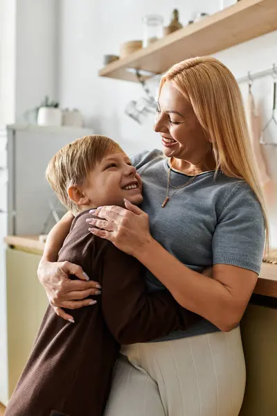 Mutter und Sohn umarmen sich innig und strahlen Wärme und Liebe in ihrem modernen Küchenbereich aus. — Stockfoto