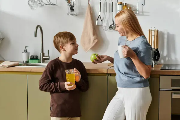 Mother shares a playful moment with her son while enjoying beverages at home. — Stock Photo