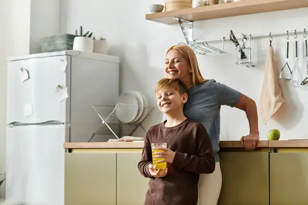A mother and son share a light moment in the kitchen over refreshing drinks. — Stock Photo