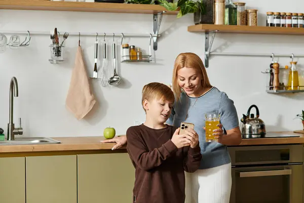 In a cozy kitchen, a mother and her son bond while exploring a mobile app together. — Stock Photo