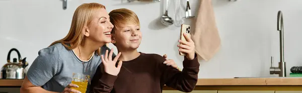 A woman and her son joyfully video call, smiling in their cozy kitchen. — Stock Photo