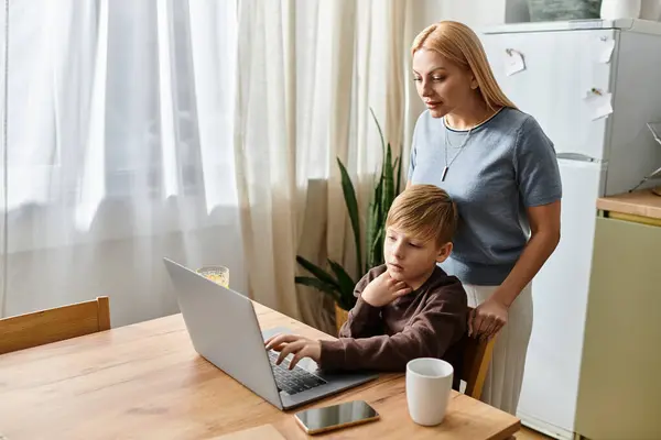 A woman supports her son with his schoolwork while they share a moment at the kitchen table. — Stock Photo