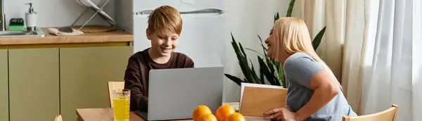 In a welcoming kitchen, a mother and son enjoy playful moments while studying on a laptop. — Stock Photo