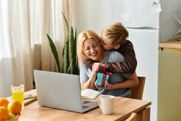 A boy surprises his mother with a small gift while she enjoys her laptop at home. — Stock Photo