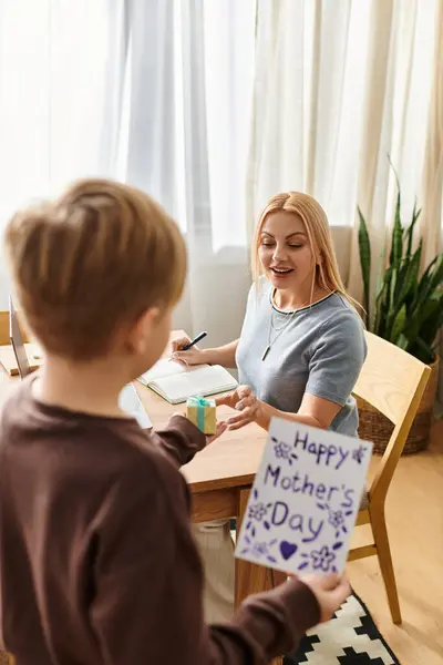 A mother joyfully receives a handmade card from her son, celebrating their bond. — Stock Photo